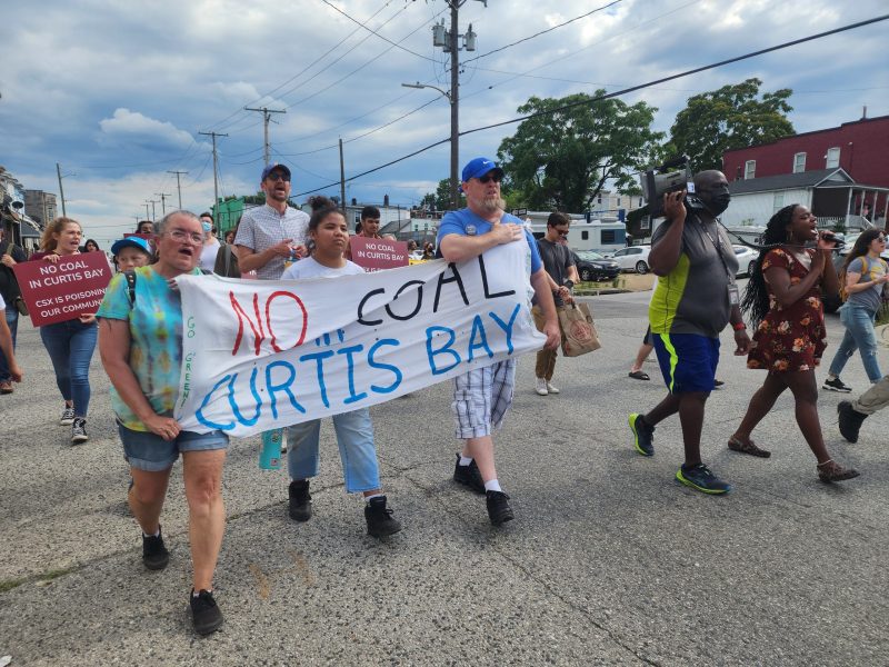 Residents of South Baltimore, local activists, and supporters from around the city march through the streets of Curtis Bay, South Baltimore, on June 10, chanting and holding signs saying "NO MORE COAL IN CURTIS BAY." Photo by Maximillian Alvarez.