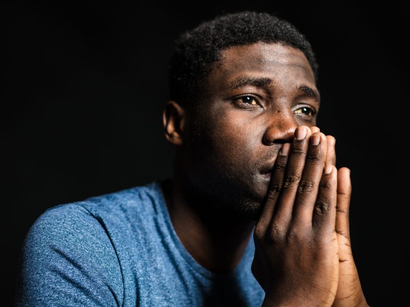 Young man looking away with hands clasped. Photo via Getty Images