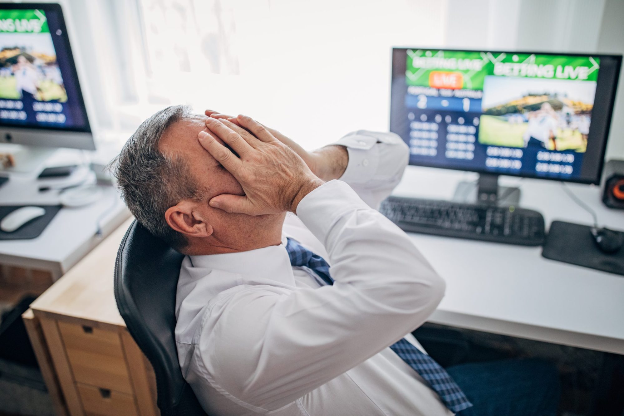 Senior business man live betting at his home office and losing. Via Getty Images