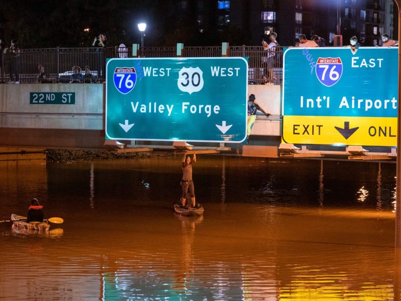 A kayaker poses for a photo under the highway sign for Valley Forge while paddling down Interstate 676