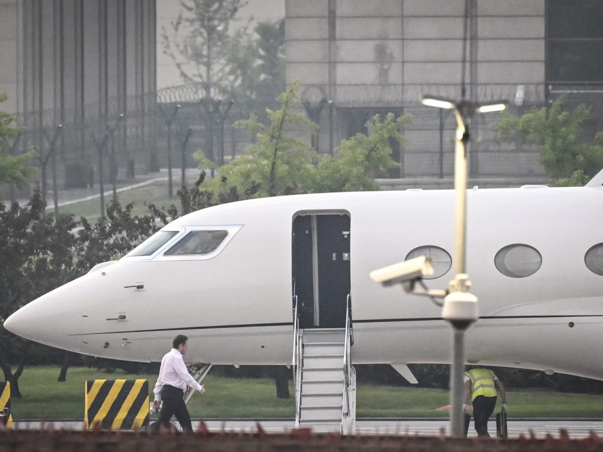 Tesla Chief Executive Officer Elon Musk (in white) boards his private jet before departing from Beijing Capital International Airport on May 31, 2023. Photo by JADE GAO/AFP via Getty Images