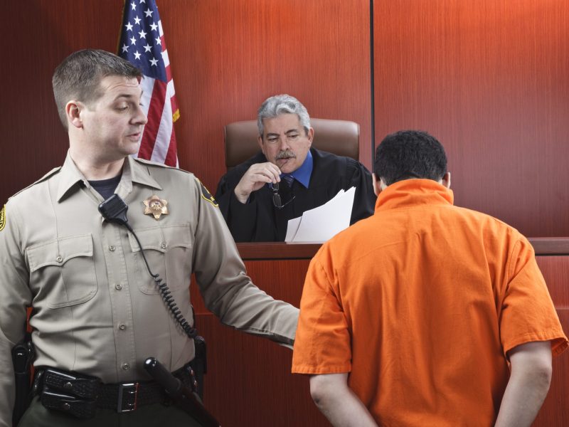 Judge speaking to a prisoner in the courtroom.