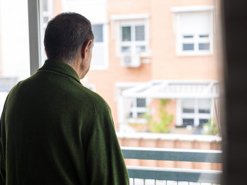 An Alzheimer’s patient looks out his window at a neighboring apartment complex.