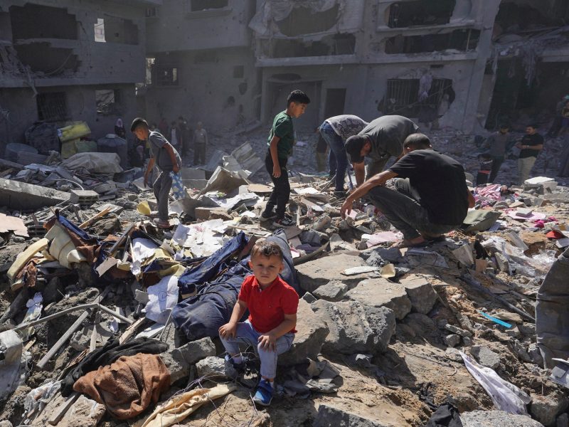 A Palestinian boy sits as people search the rubble of the Harb family home destroyed in overnight Israeli strikes in al-Bureij refugee camp in the central Gaza Strip. Photo by BASHAR TALEB/AFP via Getty Images