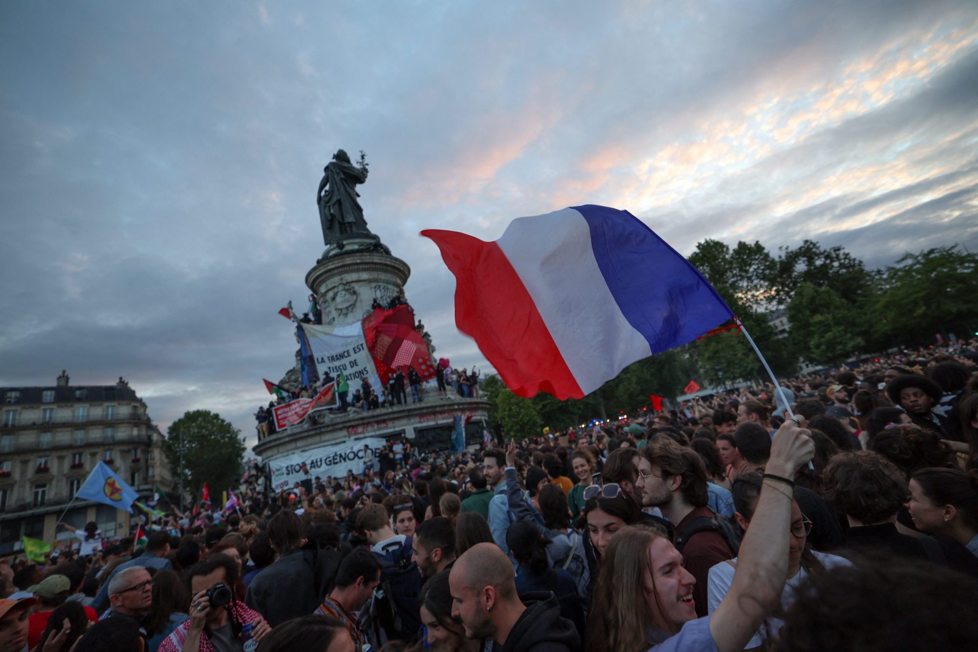 A participant waves a French national tricolor during an election night rally following the projected results of the second round of France's legislative election, at Place de la Republique in Paris on July 7, 2024. Photo by EMMANUEL DUNAND/AFP via Getty Images