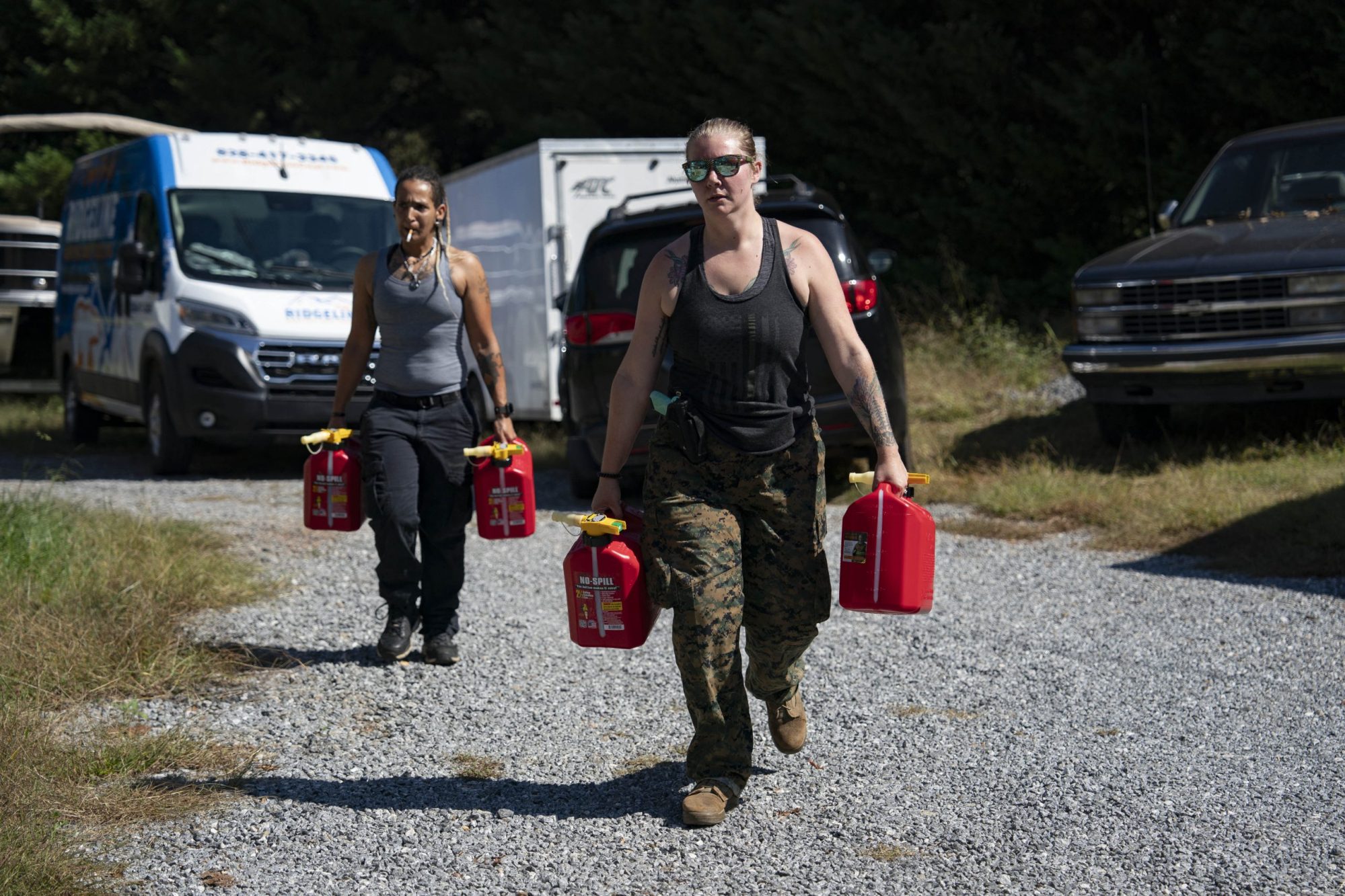 Community volunteers Candace Ramey and Jen Jordan carry gas at Ridgeline Heating and Cooling, which has turned into a relief area and community coordination center, in Bills Creek, North Carolina, on October 3, 2024, after the passage of Hurricane Helene. Photo by ALLISON JOYCE/AFP via Getty Images