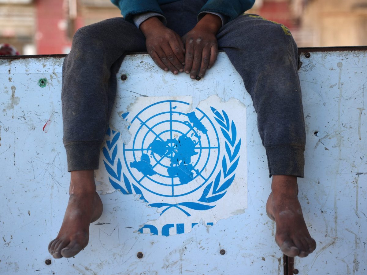 A Palestinian boy sits over a torn UNRWA sticker in Nuseirat in the central Gaza Strip on December 2, 2024, amid the ongoing war between Israel and Hamas militants. Photo by EYAD BABA/AFP via Getty Images