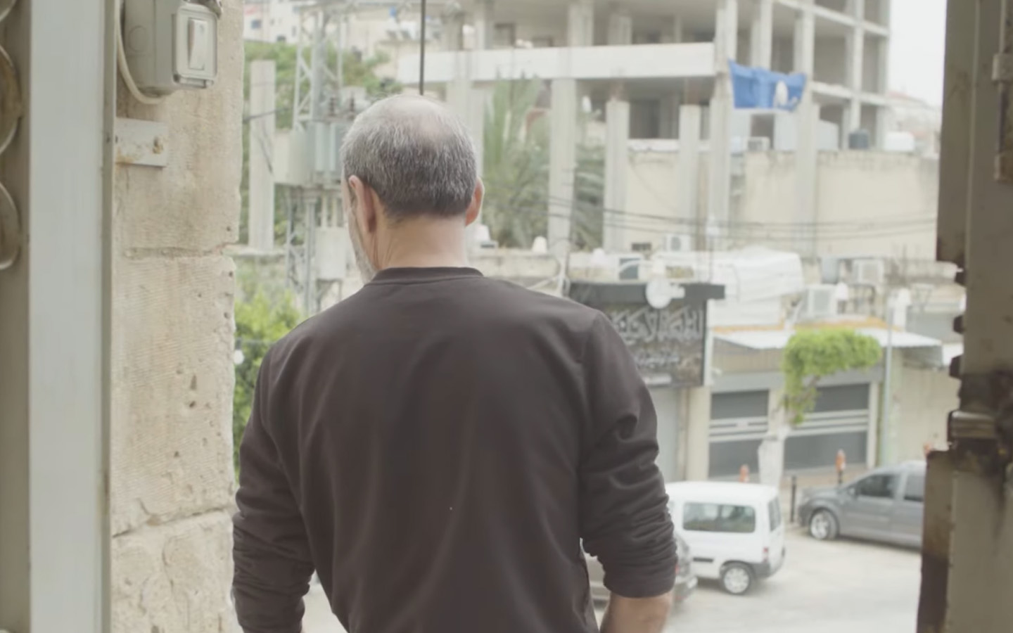 A Palestinian worker from the Gaza Strip looks out into the street in Tulkarm, West Bank. Screenshot from video by Ross Domoney